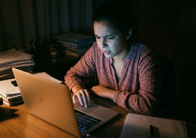Mulher pesquisando no escuro à luz do notebook